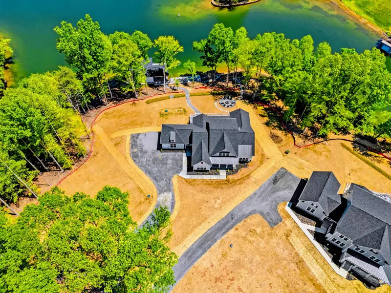 Aerial - The home, driveway with extra parking, and dock laid out along the water's edge.