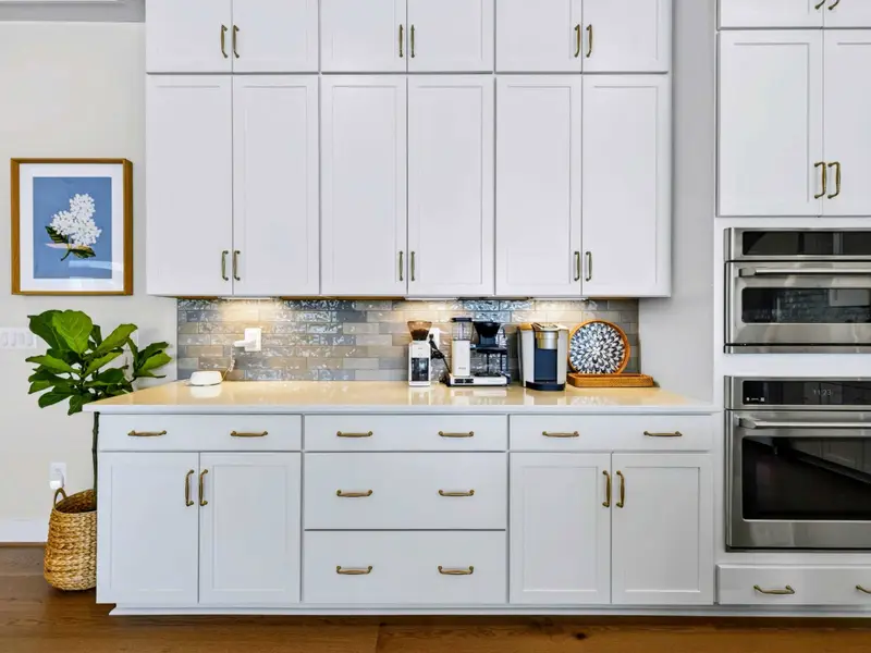 Chef's Kitchen - Detail of the coffee station with grinder, drip maker, and Keurig set against a glazed subway backsplash beneath stacked white cabinetry.