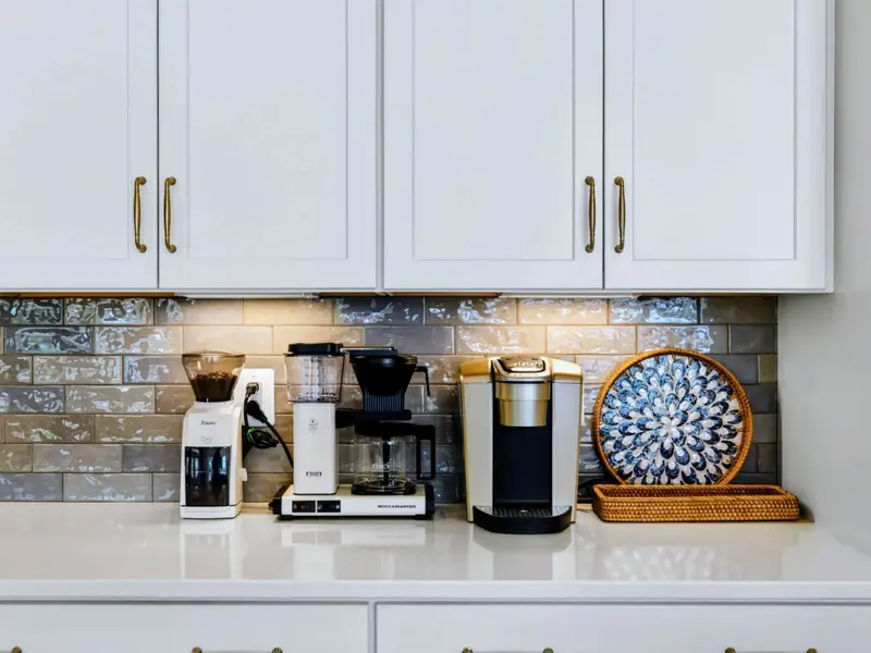 Chef's Kitchen - Tight shot of the full coffee bar, grinder and pour-over lineup glowing under cabinet lights against the iridescent tile backsplash.