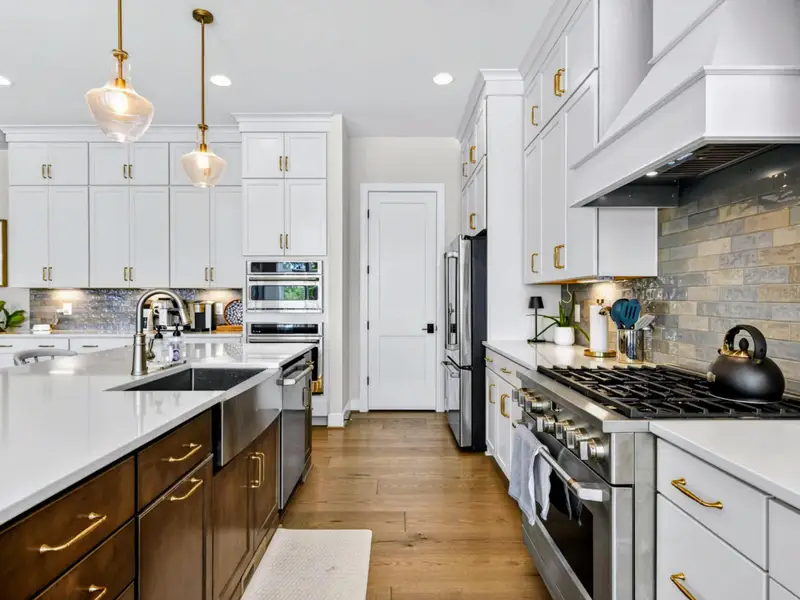 Chef's Kitchen - Long galley view pairs the white quartz island with a pro stainless range, statement hood, and a black kettle on the cooktop.