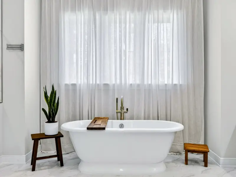 Primary Bath - The sculptural soaking tub framed by sheer drapes and tiled walls.