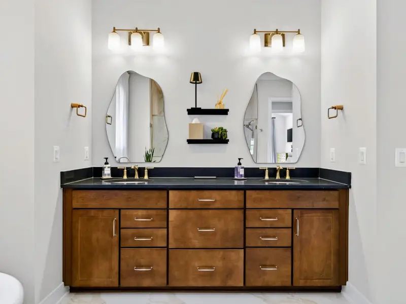 Primary Bath - A navy double vanity with arched mirrors and polished fixtures.