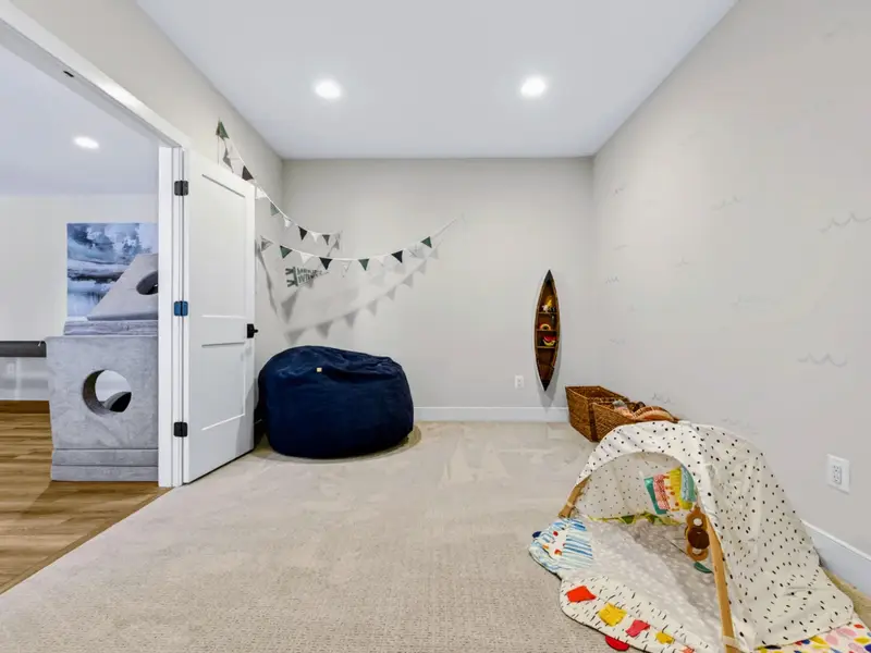 Kids' Playroom - Bright space with a Making Waves pennant banner, navy bean bag, fish-shaped wall shelf, woven baskets, and a soft baby activity mat.