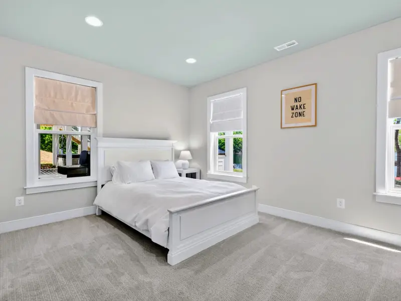 Bedroom - A queen bed beneath a playful 'No Wake Zone' print, with bright windows and lake views.