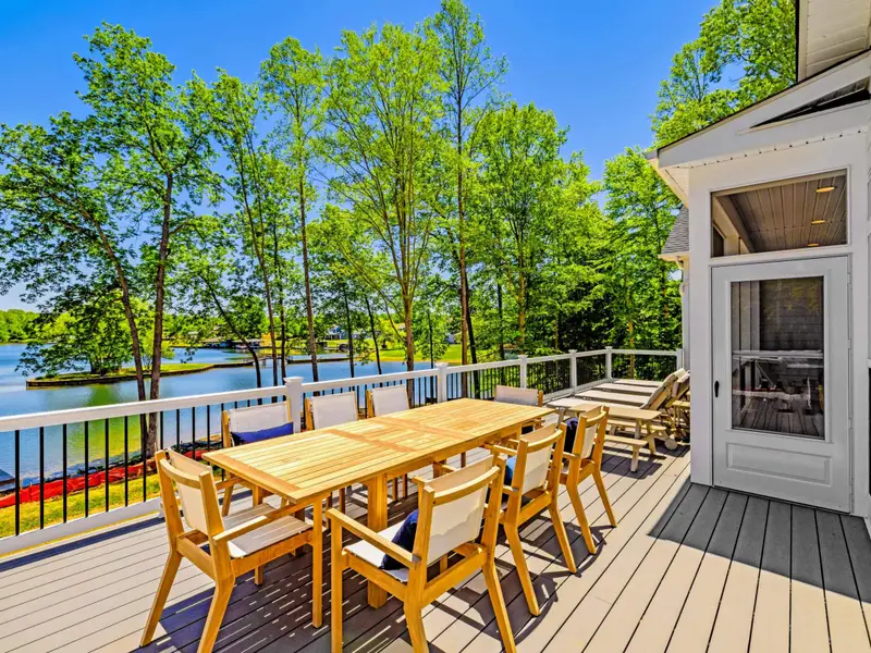 Deck - A long teak dining table set for eight stretches across the sun-soaked deck, with the lake glittering through the trees.