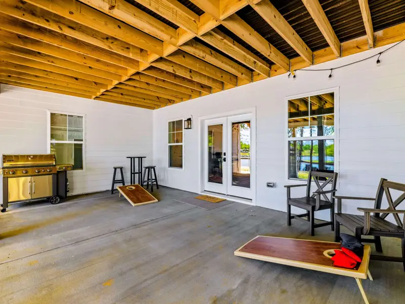 Covered Patio - A stainless gas grill, cornhole boards, and bistro seating fill this shaded lower-level space just off the lake-view doors.