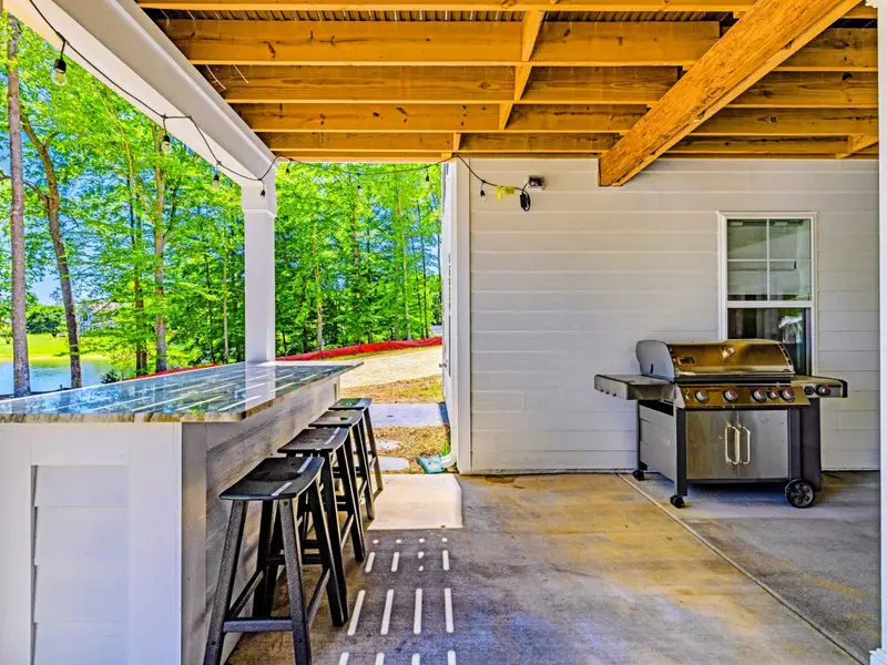 Covered Patio - A granite bar lined with stools and a stainless grill make this breezy spot ideal for cookouts steps from the lawn.