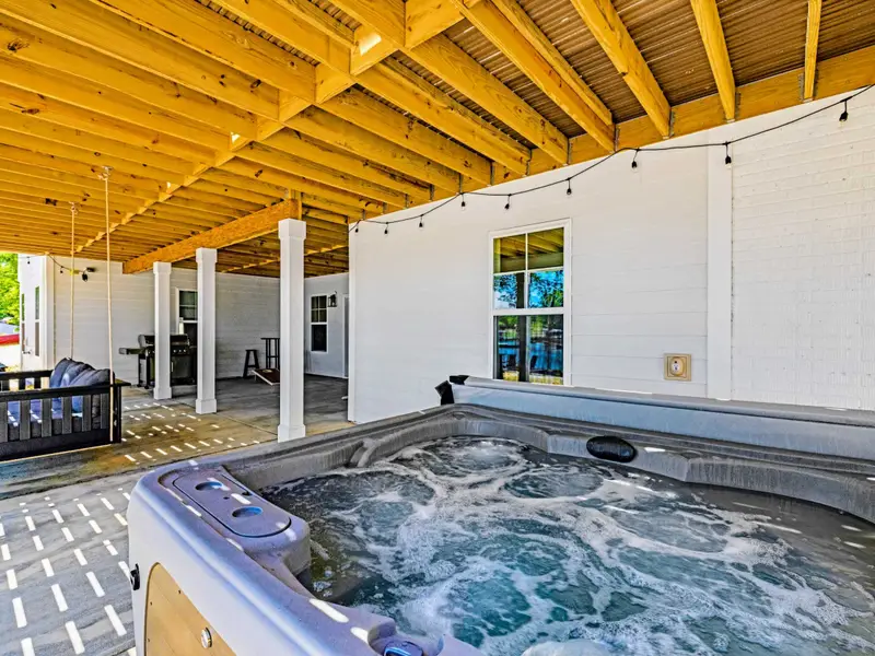 Hot Tub - Jets churn in the spacious spa under exposed wood beams, with a porch swing and string lights setting the scene for an evening soak.