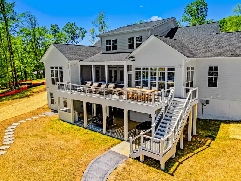 Deck - Aerial view of the home's two-tier back deck, with loungers and dining above and a shaded patio below leading to the yard.