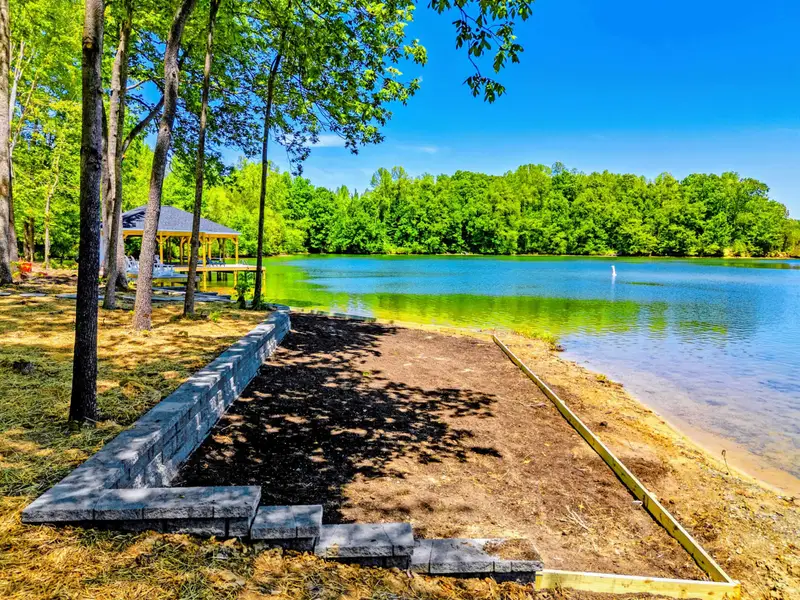 Aerial - The dock and boathouse open to wide, calm water off the point.