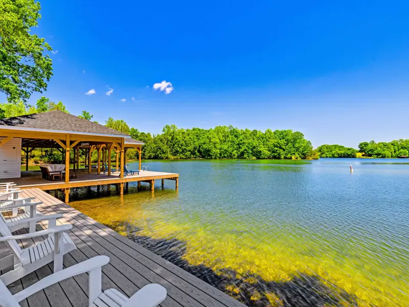 Dock & Boathouse - The covered boathouse and dock chairs look out across a broad sweep of lake under a brilliant blue sky.