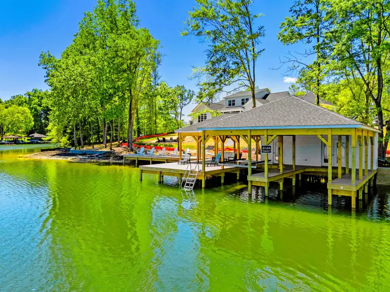 Dock & Boathouse - The covered boathouse and pavilion sit at water's edge below the home, colorful kayaks lined along the shore.