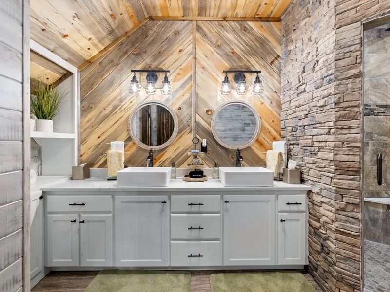 Elevate your daily routine in our ensuite oasis, complete with double sinks for space, a stone walk-in shower for serenity, and warm wood tones for a soothing atmosphere