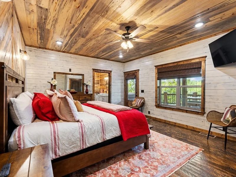 Unwind in luxury at our cabin retreat, where a king bed, spacious ensuite bathroom, and stone-tile shower with a soothing rain head and waterfall feature await. Step out onto the covered deck for a relaxing dip in the hot tub