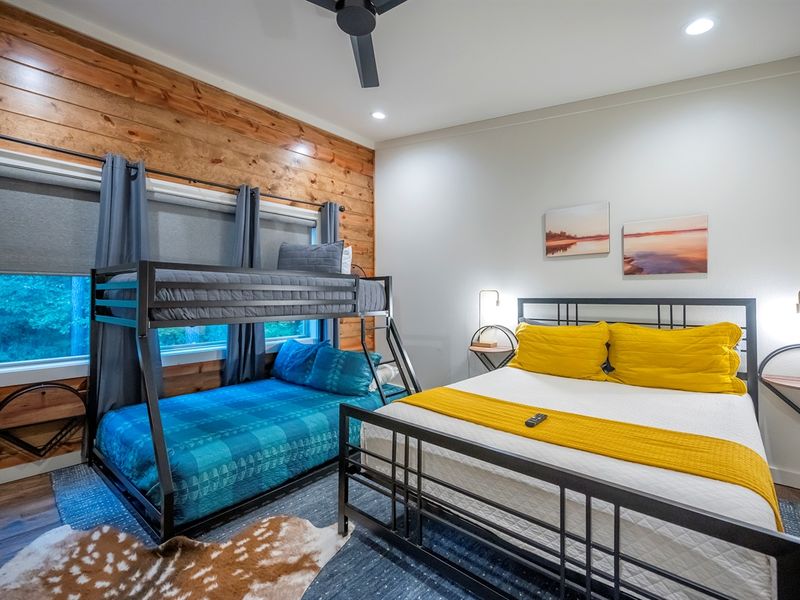 Bright and inviting guest room with a queen bed and twin-over-full bunk — perfect for families or friends who love comfort, style, and forest views