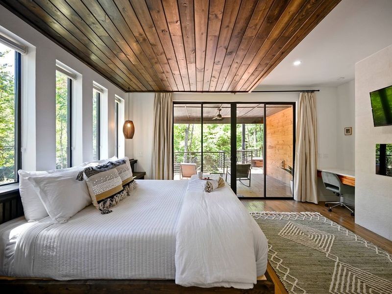 Upstairs King Bedroom — bright and airy with plenty of windows, a plush king bed, and a flat-screen TV for cozy nights in.