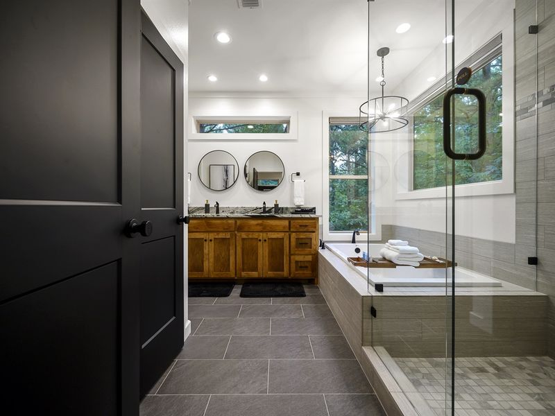 The primary bathroom is luxurious with its double sink vanity, glass frame walk in shower and soaker tub