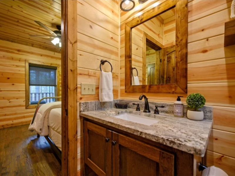 Cozy cabin bathroom interior showcasing wood-paneled walls, granite countertop, and modern fixtures, highlighting comfort