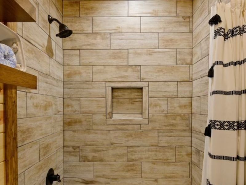 Modern shower interior featuring textured tile walls, a recessed niche, and a decorative shower curtain