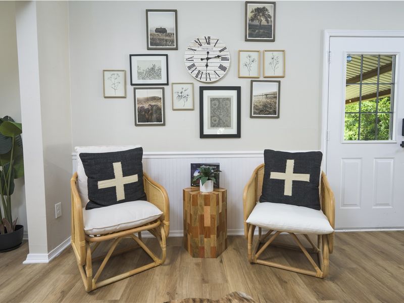 Cozy seating area featuring two rattan chairs with cross-patterned cushions, a decorative wooden side table