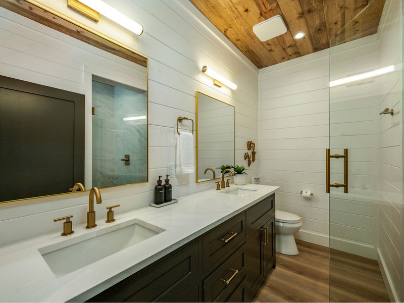 A beautifully appointed bathroom features a spacious double vanity, elegant gold fixtures, and a luxurious walk-in shower.