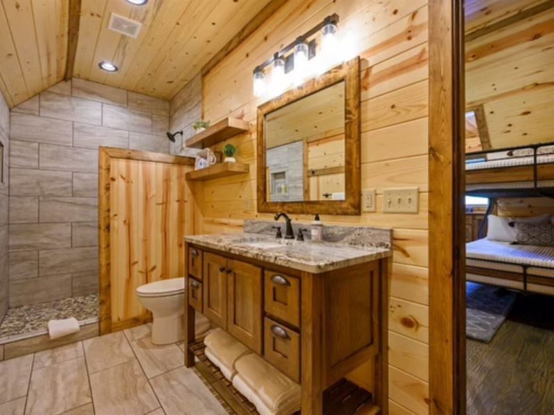 Cozy bathroom featuring wooden accents, a granite countertop, a mirror, and a walk-in shower, ideal