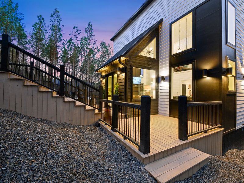 A warmly lit entry welcomes you home, with modern black siding and clean architectural lines.