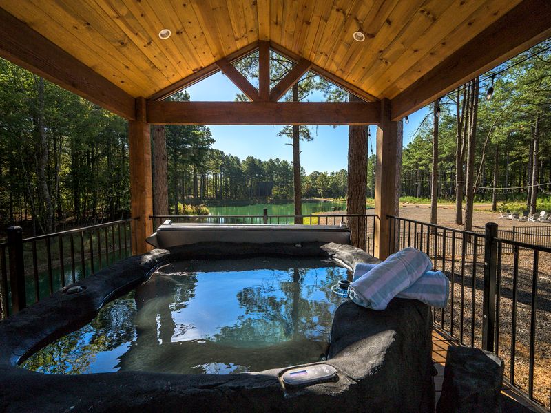 Private hot tub with serene lake views and surrounding pine trees at Bear Lake Lodge