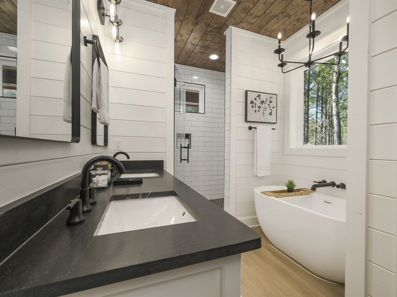 The attached bathroom features double vanities and a luxurious soaking tub.