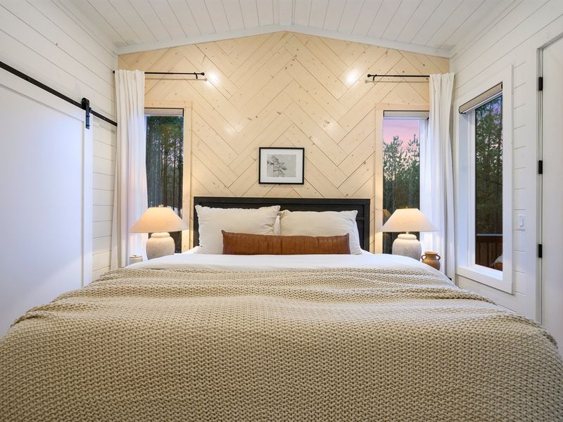 Unwind in this serene bedroom featuring a king bed and warm wood accent wall.