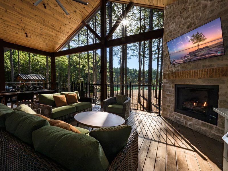 Spacious covered deck at Bear Lake Lodge featuring comfortable seating, a stone fireplace