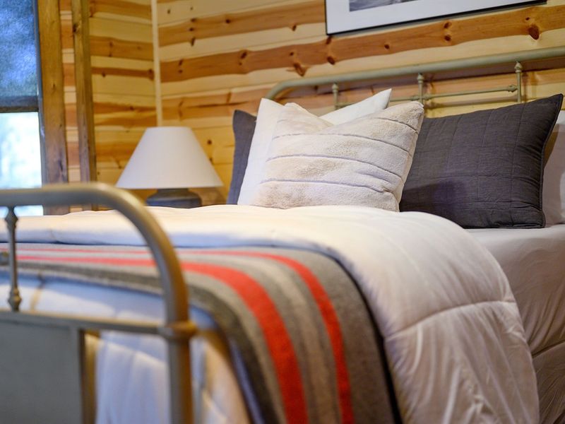 Cozy bedroom featuring a stylish bed with decorative pillows, a soft quilt, and a bedside