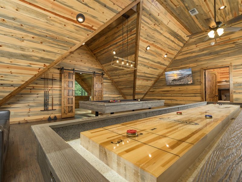 Cozy cabin interior featuring a game room with a pool table and shuffleboard, showcasing comfortable