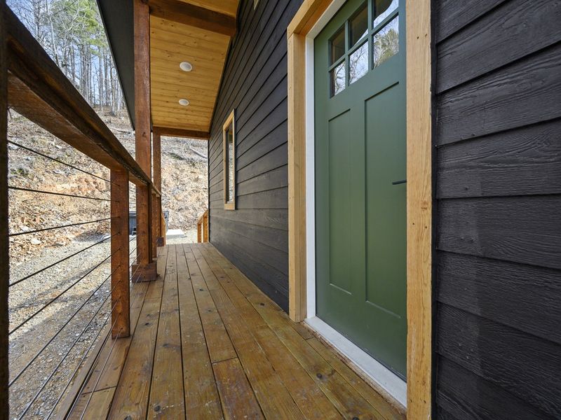 Step into serenity at this idyllic woodland hideaway, where the green door beckons you to unwind on the sun-kissed porch and soak in the peace and quiet.