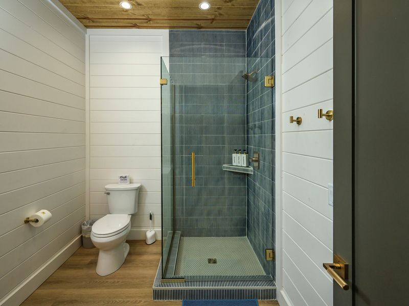 Custom tile work, brushed-gold fixtures, and a spacious design create a relaxing shower experience with a touch of luxury.