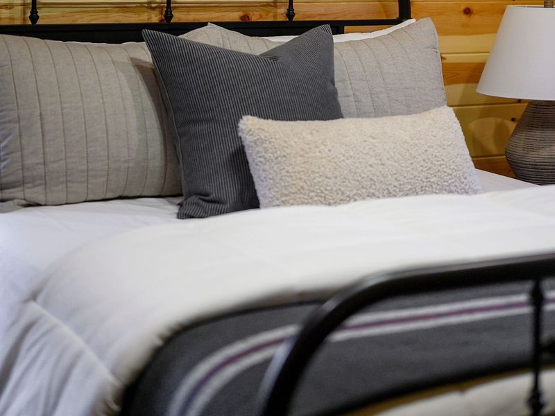 Cozy bedroom featuring a neatly made bed with decorative pillows in shades of gray