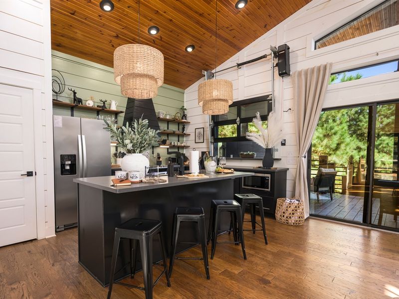 Warm wood ceilings, sculptural pendant lights, and an inviting layout make this kitchen the heart of the cabin