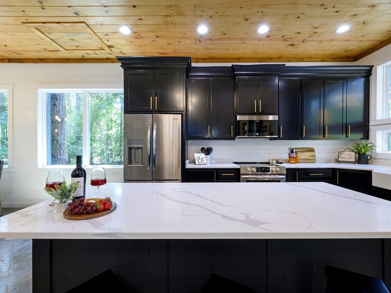 Gather around this stunning chef’s kitchen — sleek black cabinetry, quartz countertops, and forest views that turn every meal into a moment worth savoring