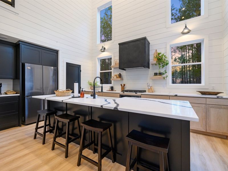 Soaring ceilings and walls of windows fill the open-concept kitchen with natural light and forest views.