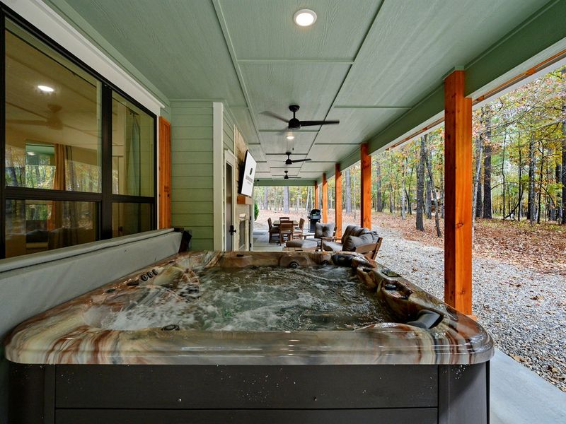 Covered outdoor hot tub with bubbling jets and forest views—perfect for relaxing during your Broken Bow getaway