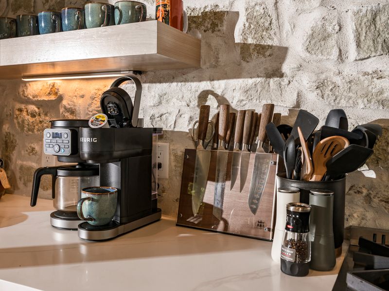 Stylish kitchen countertop featuring a Keurig coffee maker with a filled mug, wooden utensils