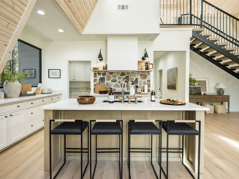 The designer kitchen features a gorgeous stone backsplash, a butler pantry, and a large window with private forest views