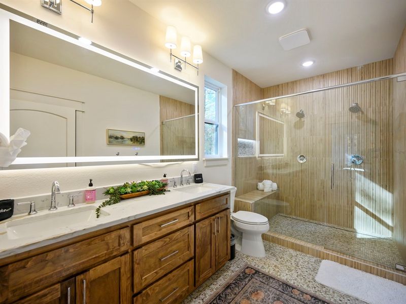 Spacious bathroom with double vanity, LED mirror, large walk-in shower, and warm rustic finishes—perfect for relaxing after your Broken Bow adventures. 🌲🛁
