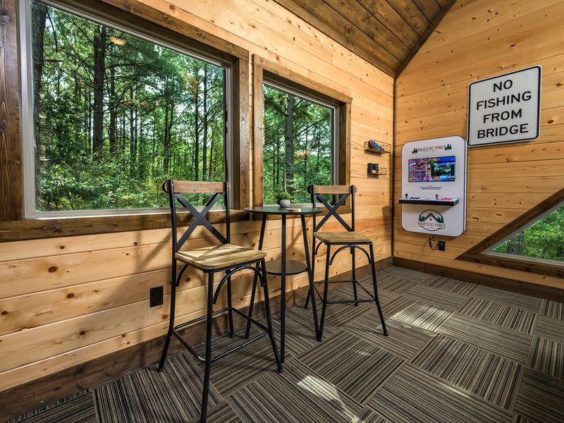 Enjoy forest views from the cozy game loft, featuring arcade fun and a charming seating area.