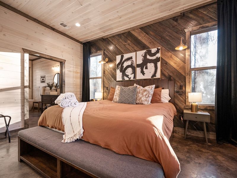 Cozy rustic retreat with a king bed, warm wood accents, and serene forest views.