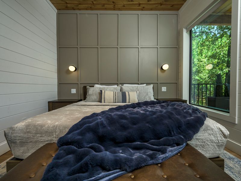 Wake up to beautiful wooded and lake views from this peaceful primary suite, with direct access to the outdoor deck.