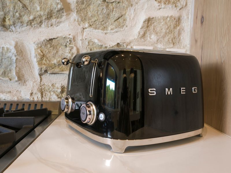 Stylish black SMEG toaster sits on a kitchen countertop, showcasing a well-appointed kitchen with modern