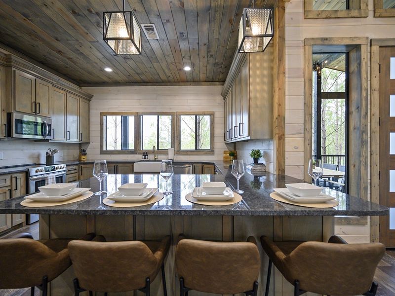 Experience the charm of cabin living with this inviting kitchen setup - a large island and chic bar stools perfect for enjoying a morning coffee or a home-cooked meal