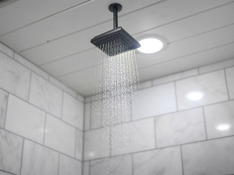 Wash away your worries under a luxurious cascade of water in this sleek white tiled shower.