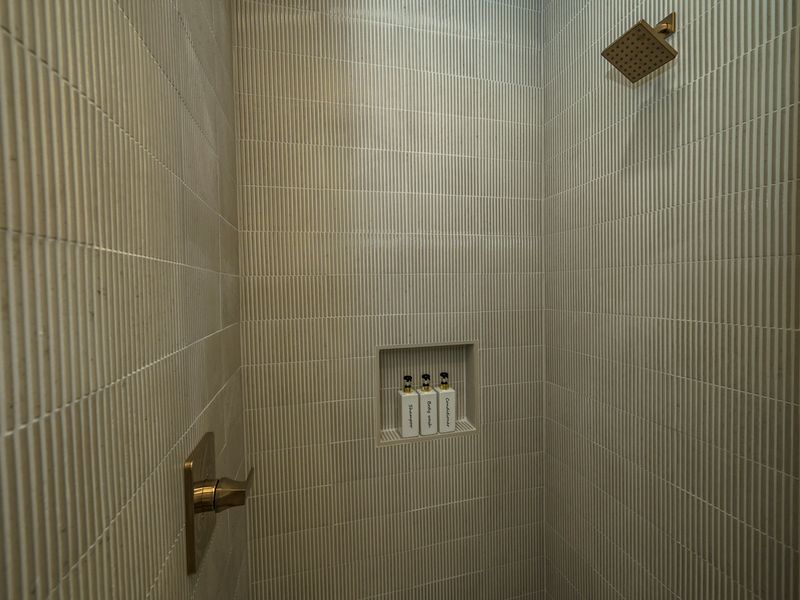Thoughtful details make this shower feel luxurious, from the rainfall shower head to the built-in shelf stocked with essentials.